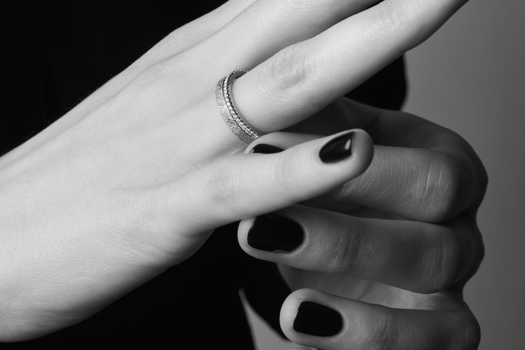 Eine Frau, die sich den Brillant Meteoriten Ring an den Finger steckt.