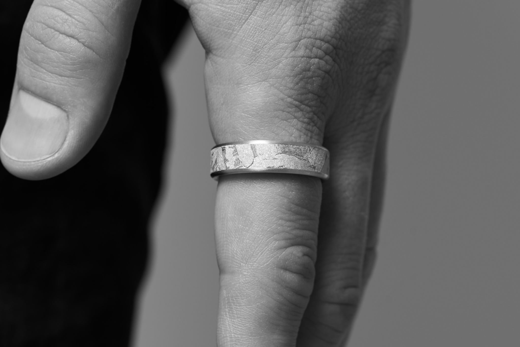 Eine Männerhand trägt den Meteoriten Ring am Zeigefinger.